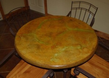 Round marble-topped table with metal chairs in a dining area. Round wooden table with a yellowish-green marble top in a dining room.