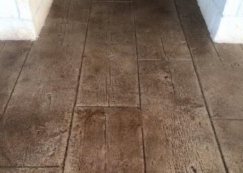 Stamped concrete porch in front of a black door with white brick walls. Stamped concrete porch in front of a black door with white brick walls.