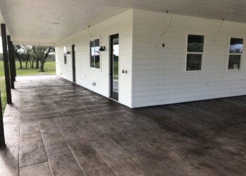Stamped concrete patio outside a white house in a rural area. Stamped concrete patio outside a white house in a rural area.