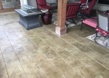 Stamped concrete patio with furniture and decorative elements in a residential setting. Stamped concrete patio with furniture and decorative elements in a residential setting.