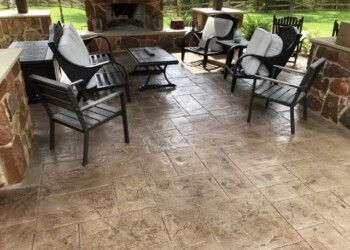 Stamped concrete patio with outdoor seating and fireplace in a backyard. Stamped concrete patio with outdoor furniture and fireplace in a backyard setting.