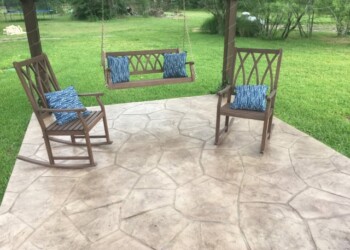 Stamped concrete patio with wooden chairs and swing in a green backyard. Stamped concrete patio with wooden chairs and swing in a green backyard.