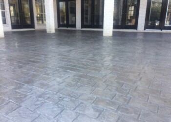 Stamped overlays on concrete patio at a commercial building in Eads, Tennessee. Stamped concrete patio with a textured brick pattern outside a commercial building.