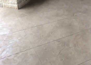 Stamped overlays on concrete patio at a residential property in Eads, Tennessee. Stamped concrete patio with a smooth, textured finish near a brick wall and door.
