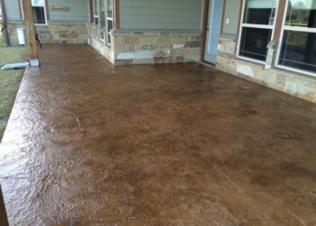 Stamped overlays on a concrete patio at a residential property in Eads, Tennessee. Stamped concrete patio with a brown finish outside a house in Eads, Tennessee.