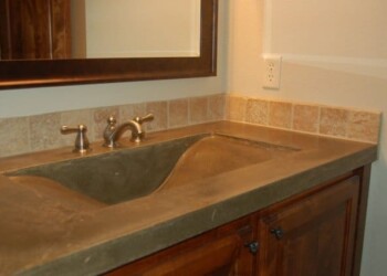 Concrete bathroom vanity with a sink and backsplash in a home. Concrete bathroom vanity with a sink and backsplash in a home.