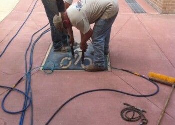 Workers installing or repairing concrete on a sidewalk in a commercial area. Two workers installing or repairing concrete on a sidewalk in a commercial area.