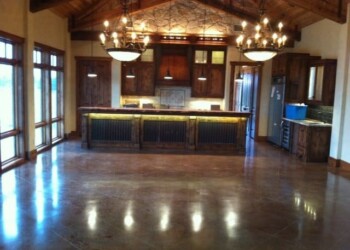 Polished concrete floor in a rustic kitchen with wooden cabinets and high vaulted ceiling. Polished concrete floor in a rustic kitchen with wooden cabinets and high vaulted ceiling.