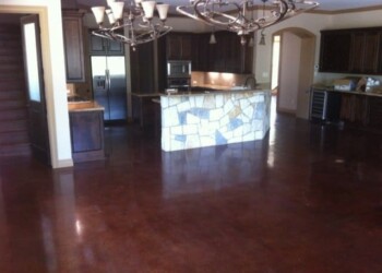 Polished concrete floor in a kitchen with dark wood cabinets and a stone island. Polished concrete floor in a spacious kitchen and dining area.