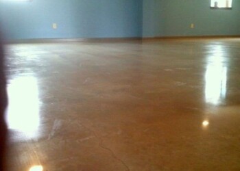 Finished polished concrete floor in a spacious room, part of a concrete service project in Ephrata. Polished concrete floor in a large room with blue walls and wooden baseboards.