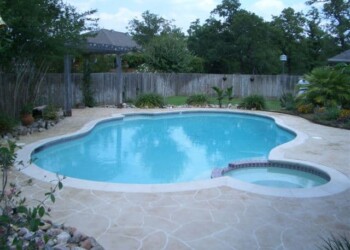 Stamped concrete pool deck in a backyard in Euless, Texas. In-ground swimming pool with stamped concrete deck in a backyard.