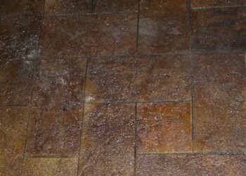 Stamped overlays on a concrete patio in Eads, Tennessee, showcasing a textured, brown finish. Stamped concrete patio with a textured, brown finish and white speckles.