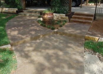 Stamped overlays on concrete walkway and steps at a residential property. Stamped concrete walkway with steps and garden bed in front of a house.