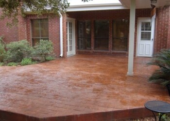 Finished stamped overlays on a backyard patio in Eads, Tennessee. Stamped concrete patio with a reddish-brown finish in a residential backyard.