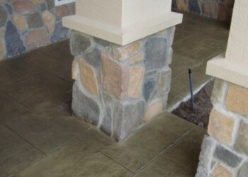 Stamped overlays on concrete porch with stone veneer columns in Eads, Tennessee. Stamped concrete with stone veneer columns at a residential porch in Eads, Tennessee.