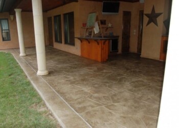 Stamped overlays on the concrete patio at a residential property in Eads, Tennessee. Stamped concrete patio with a decorative pattern in front of a house.