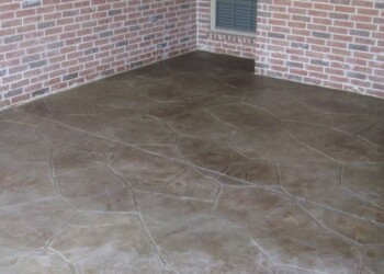Stamped overlays on concrete patio in front of a brick house. Stamped concrete patio with a stone pattern in front of a brick house.